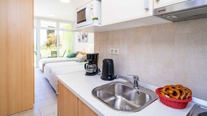 A modern kitchen with a stainless steel sink, a microwave, a coffee maker, and a basket of pretzels. - Apartments Subrenum (Zupa dubrovacka)