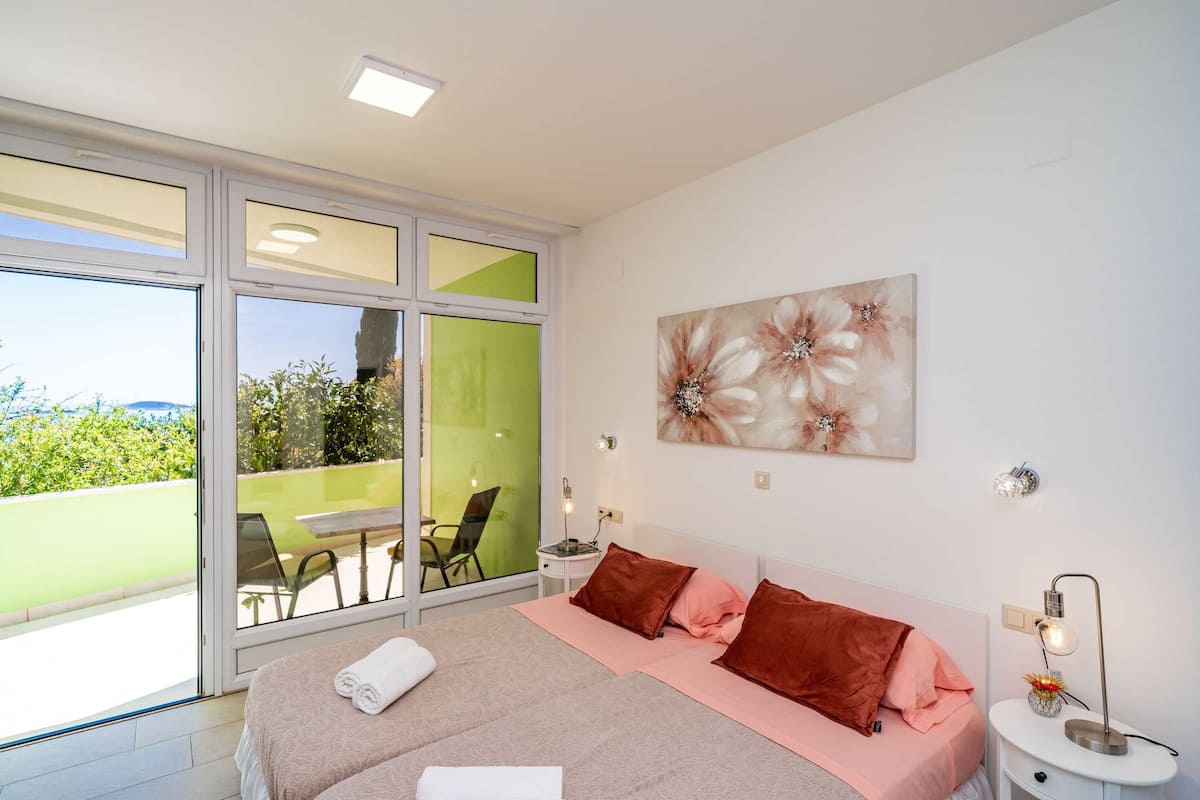 A bedroom with a bed, pillows, a nightstand, a lamp, and a painting.