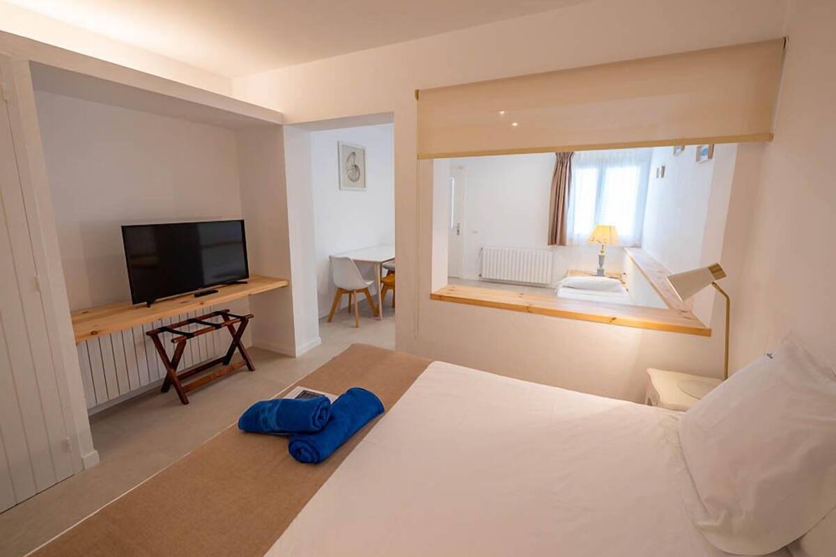 Una habitación de hotel con cama, televisión, escritorio y espejo.