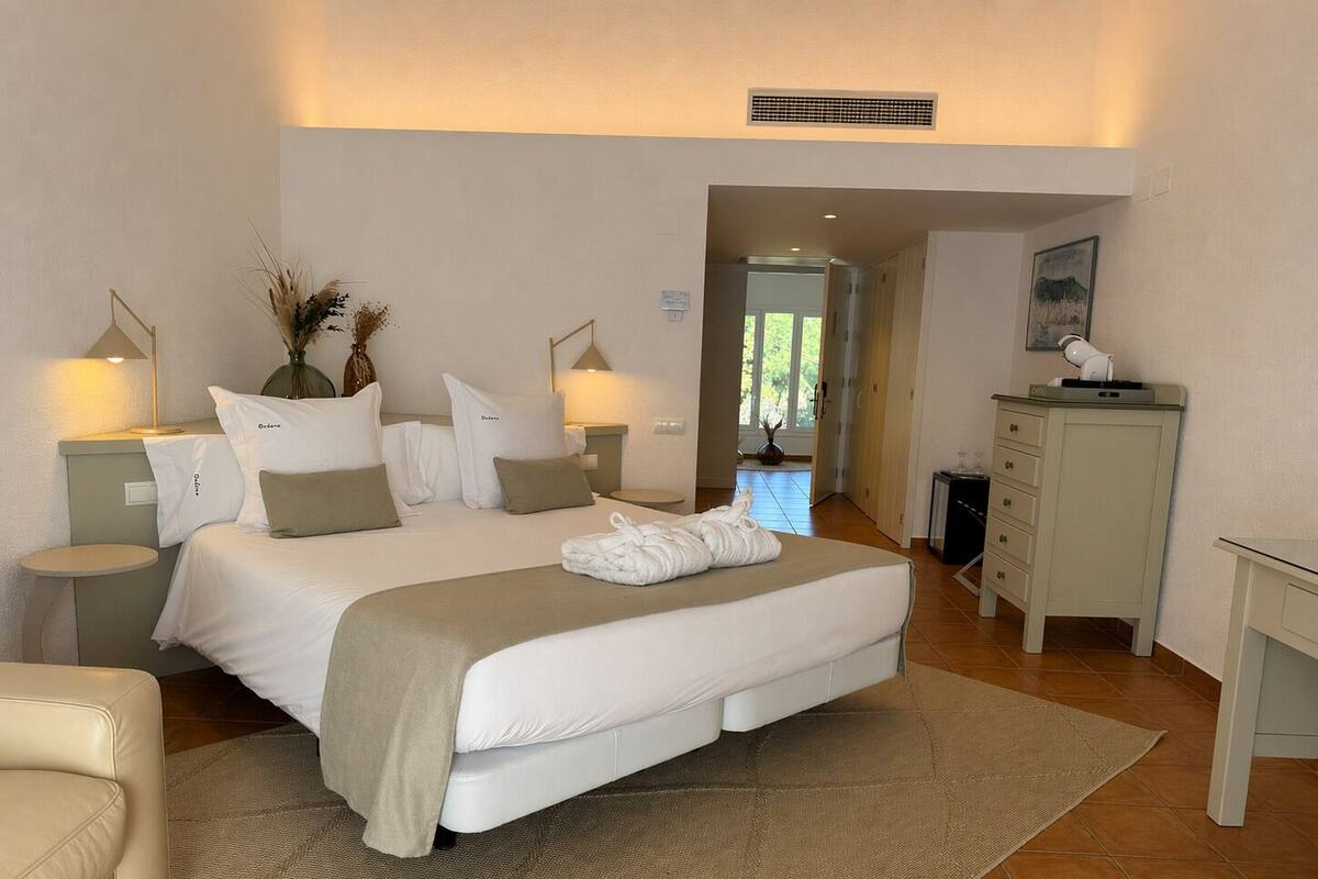 Un dormitorio con una cama grande, mesitas de noche, un escritorio y una silla.