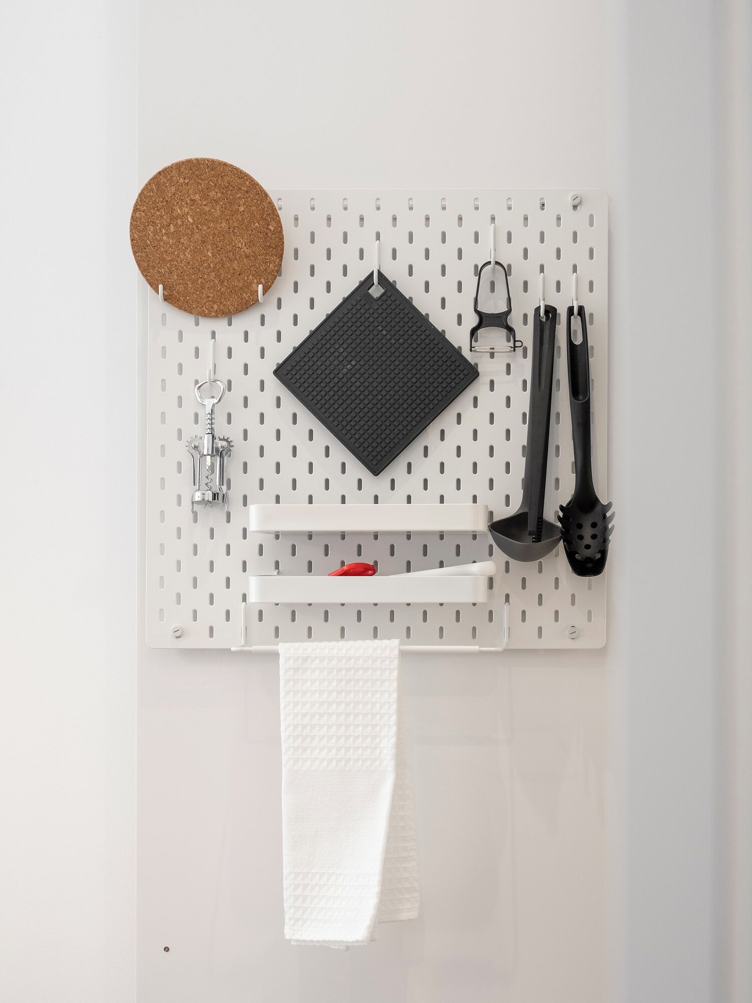 Una pared con tablero de corcho y diversos utensilios de cocina.