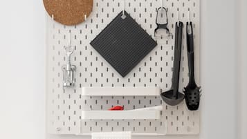 A pegboard wall with various kitchen utensils and a cork coaster.