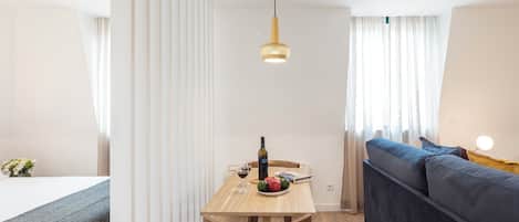 Una habitación moderna y bien iluminada con una mesa de comedor de madera, un sofá y una cama.