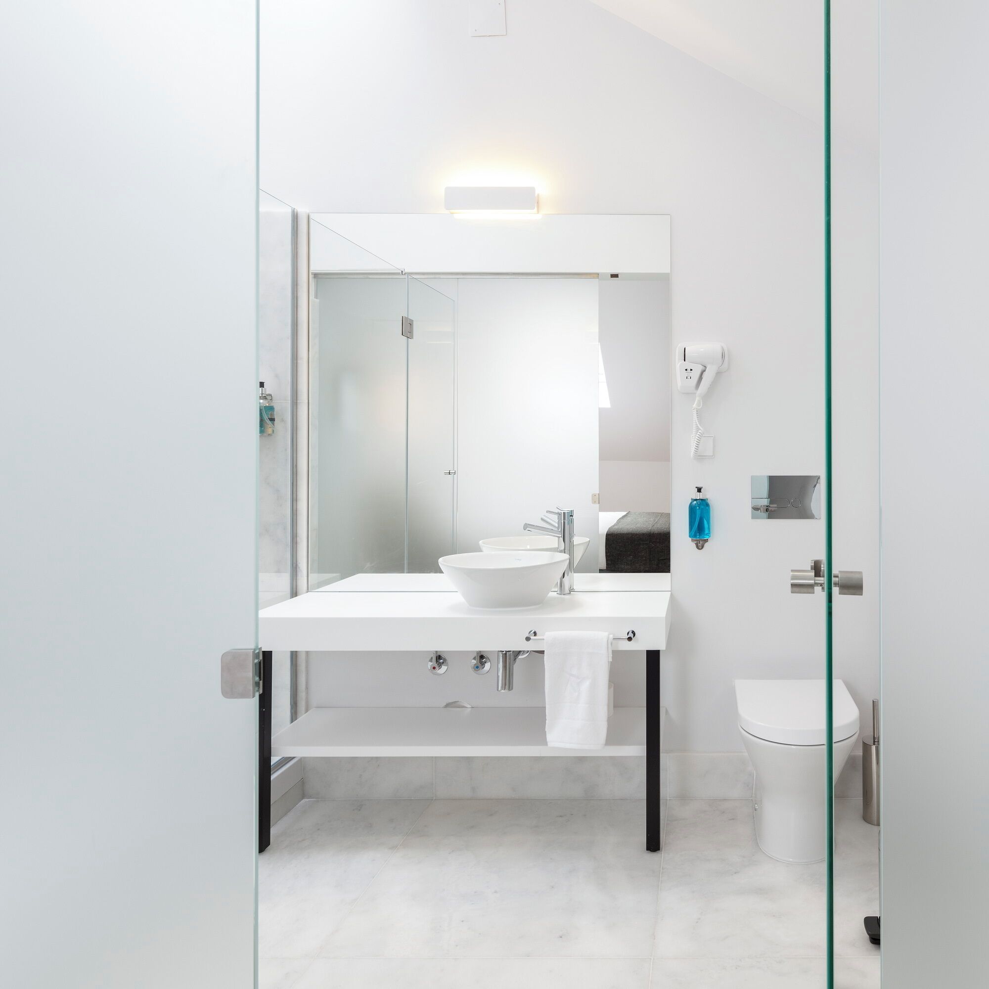 A modern bathroom with a white sink, mirror, and toilet.