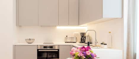 Una cocina moderna con una mesa de comedor, sillas, una cafetera y un florero.