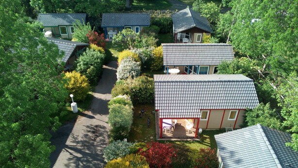 A residential area with multiple houses, each with a tiled roof and surrounded by well-maintained gardens. - Camping les Craoues (Capvern)