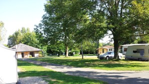 A residential area with a gravel driveway, a house, and a mobile home. - Camping les Craoues (Capvern)