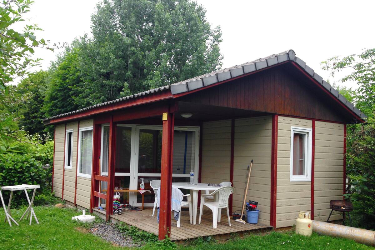 Eine kleine Holzhütte mit Veranda, Tisch und Stühlen.