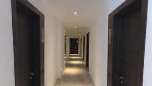 A long, narrow hallway with dark wooden doors on either side, leading to a central door at the end. - Hotel Resort Le Vele (Domaso)