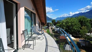 A balcony with two chairs, a table, and a view of mountains and a lake. - Hotel Resort Le Vele (Domaso)