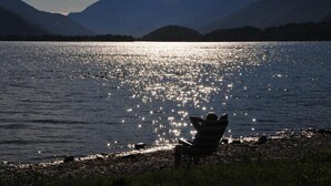 A person sitting on a chair by a lake with mountains in the background. - Hotel Resort Le Vele (Domaso)