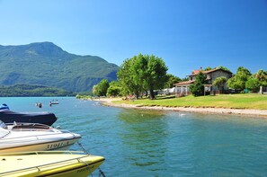 A lakeside view with boats, a grassy area, and buildings.