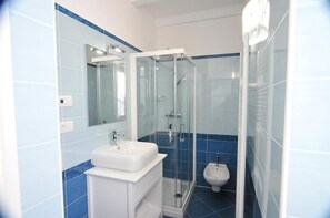 A modern bathroom with a glass-enclosed shower, a white sink, and a bidet.