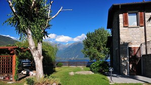 Ein Steingebäude mit einer Holzterrasse und Blick auf einen See und Berge.