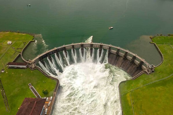 A large dam with water flowing through its gates, surrounded by green fields and a small body of water. - La Cubana Colón (Colon)
