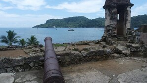 A historical cannon overlooking a body of water with boats and a small island in the distance. - La Cubana Hotel & Residencial (Colon)