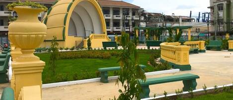 A courtyard with a large yellow structure, green benches, and a well-maintained lawn.