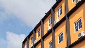 A multi-story hotel with balconies, air conditioning units, and a street in front with parked cars and traffic cones. - La Cubana Hotel & Residencial (Colon)