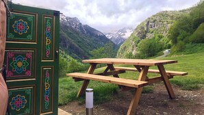 Una mesa de picnic en una zona montañosa con un edificio verde que presenta coloridos diseños geométricos.
