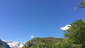 Paisaje montañoso con yurtas y cielo azul despejado.