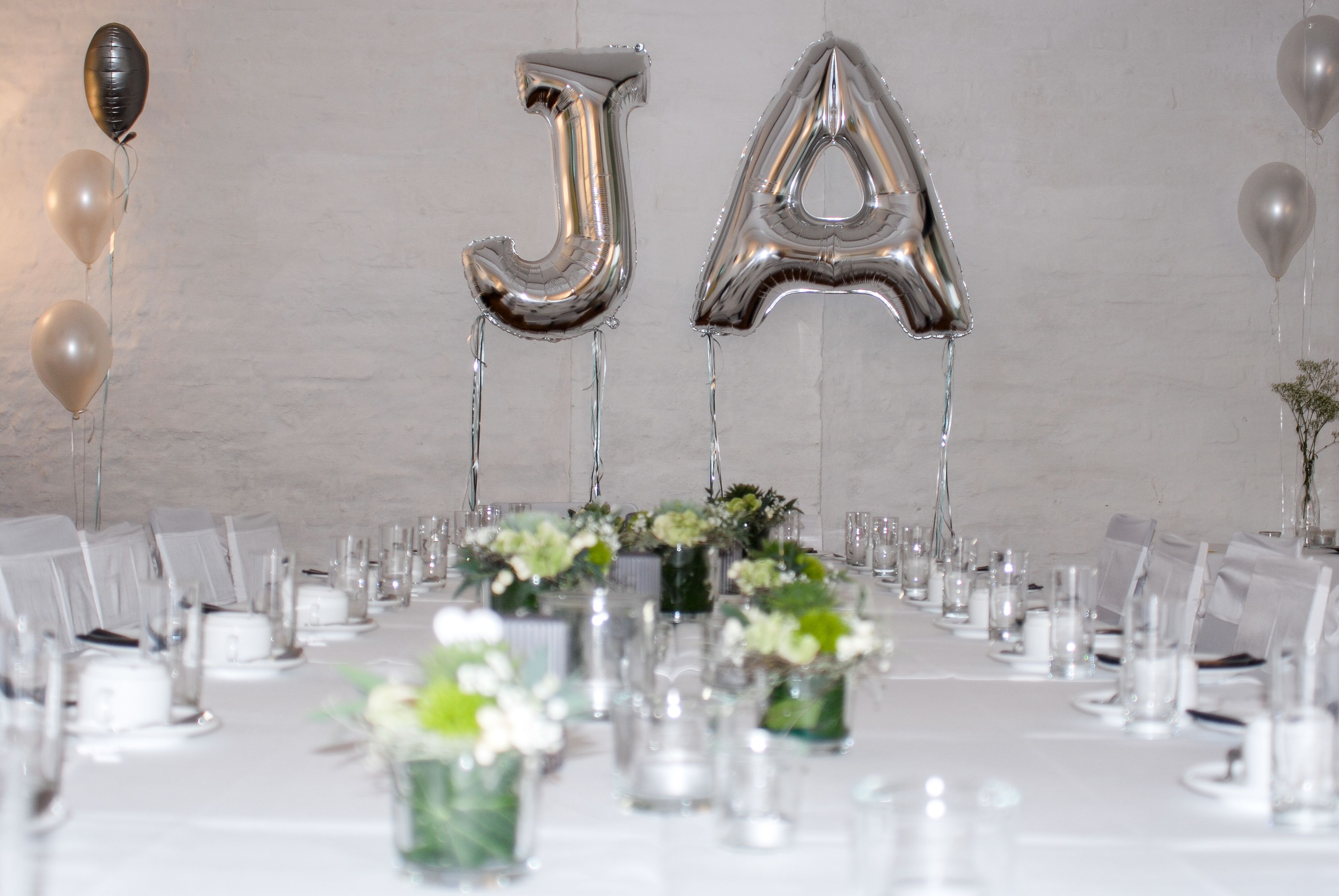 A banquet table set with chairs, glassware, and floral centerpieces.