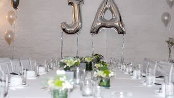 A banquet table set with chairs, glassware, and floral centerpieces.