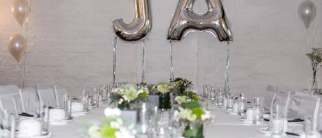 A banquet table set with chairs, glassware, and floral centerpieces.