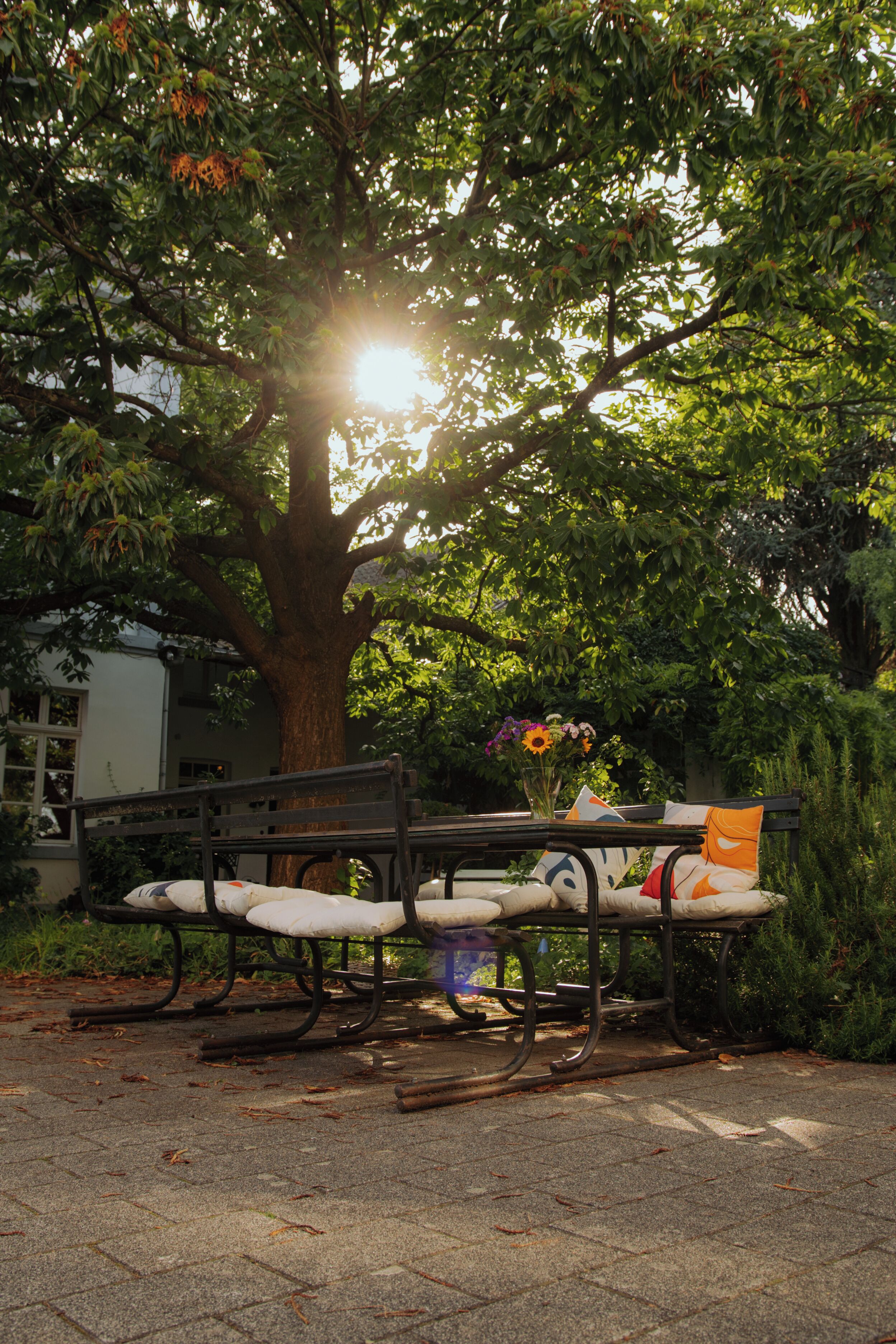 Un banc avec un coussin et un vase de fleurs dans un parc.