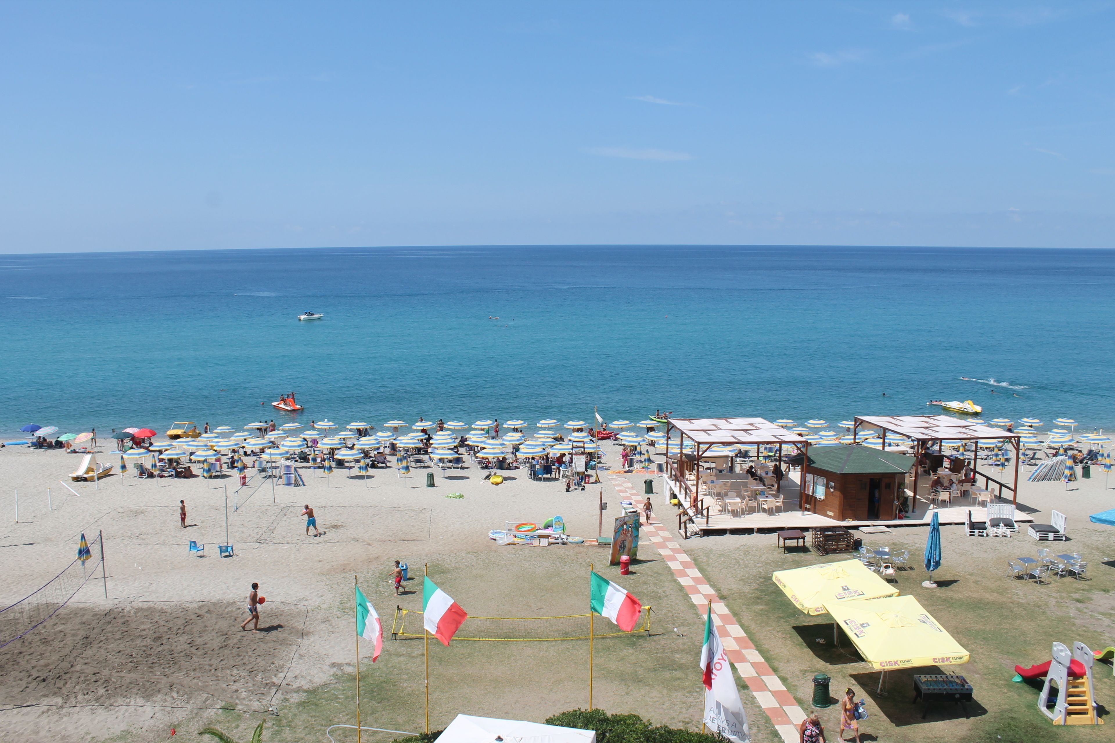 Una playa con sombrillas, sillas de playa y una torre de salvavidas.