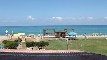 A beachside property with a wooden structure, outdoor seating, and a view of the sea.
