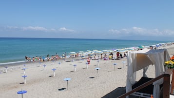 Een privéstrand, ligstoelen aan het strand, parasols, duiken