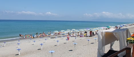 Een privéstrand, ligstoelen aan het strand, parasols, duiken