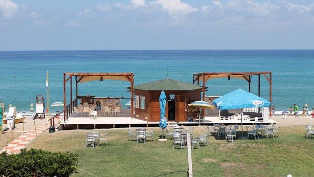 A beachside wooden structure with outdoor seating and a view of the ocean. - Hotel South Paradise (Palmi)