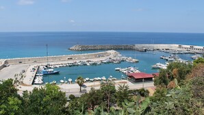 A marina with boats docked, a stone breakwater, and a clear blue sky. - Hotel South Paradise (Palmi)