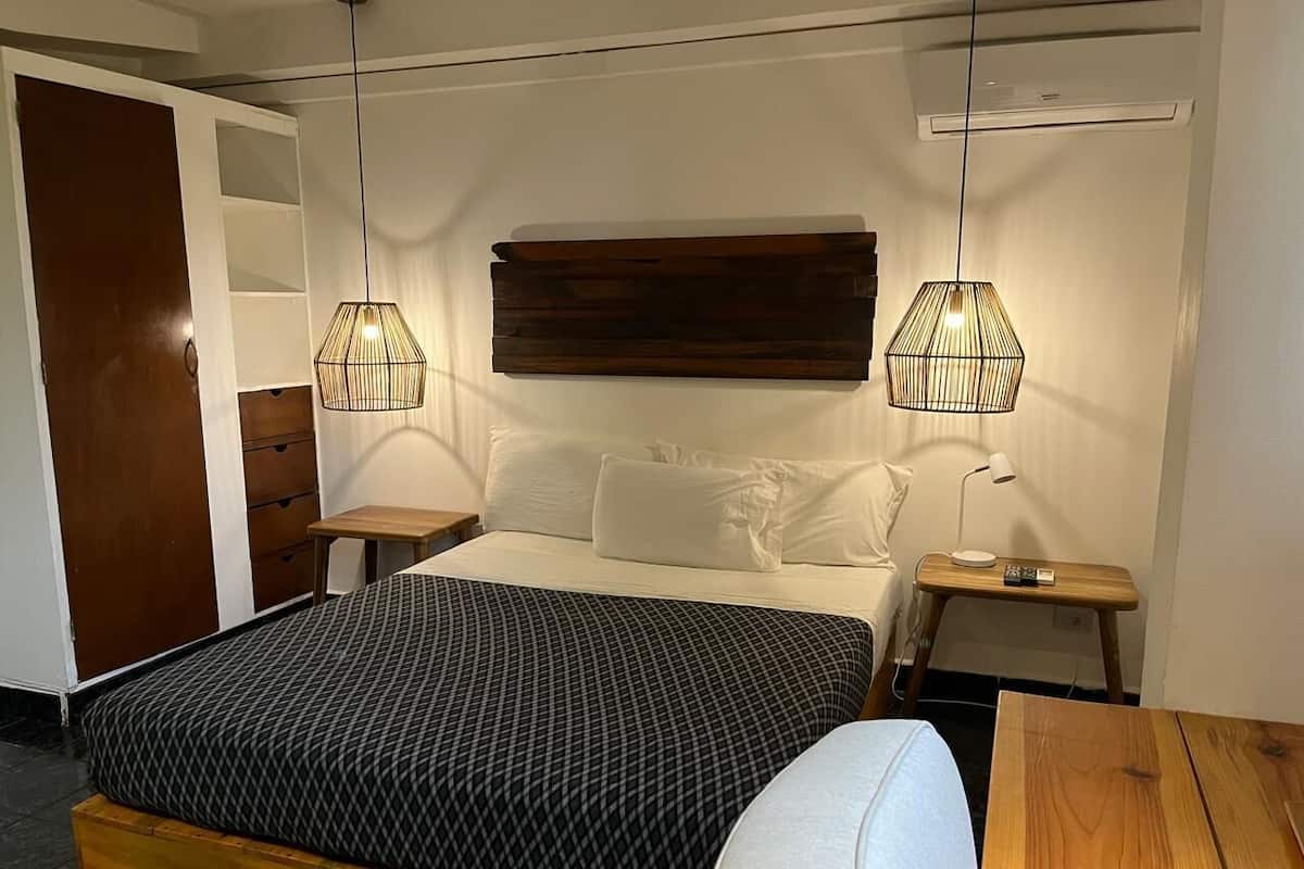 Ein ordentlich eingerichtetes Schlafzimmer mit einem Bett, Nachttischen und einem Nachttisch aus Holz.