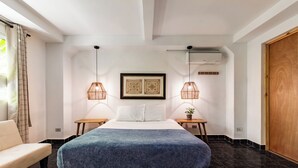 Een moderne slaapkamer met een groot bed, twee nachtkastjes, een houten bankje, een potplant en een grote houten deur.
