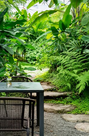 Sit and enjoy the serene garden views from this outdoor seating area surrounded by lush greenery and natural elements.