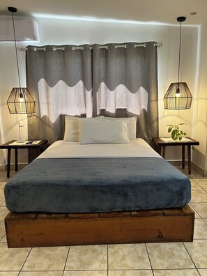 Cozy retreat with a large bed, bedside tables, and a small table with a plant.