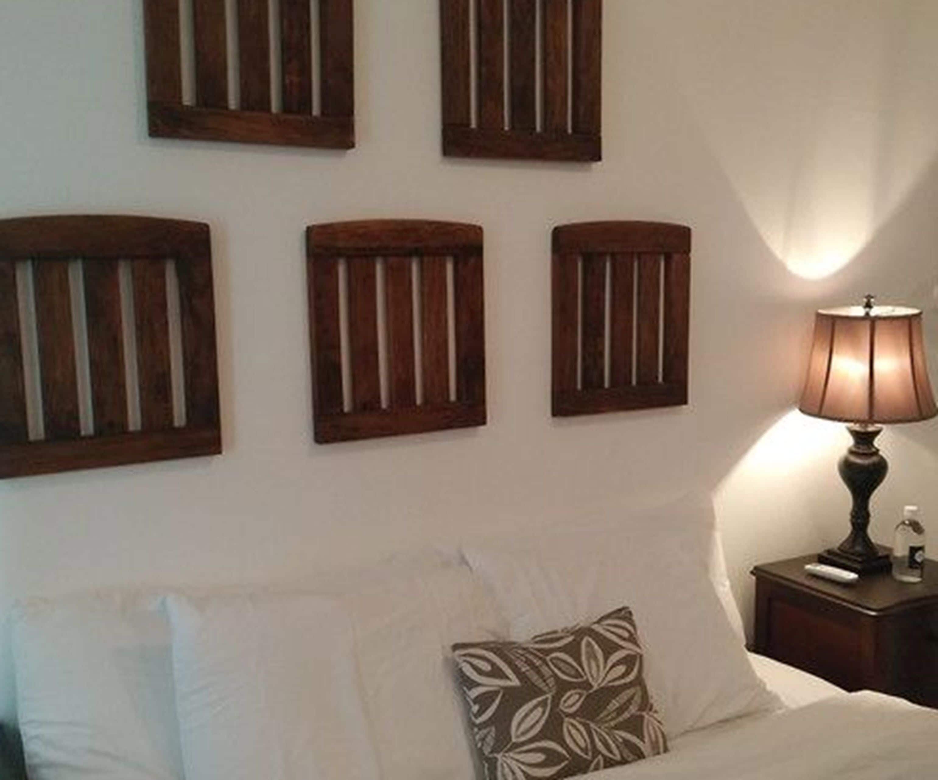 Ein Schlafzimmer mit einem Bett, Kissen, einem Nachttisch, einer Lampe und drei Wandleuchten.