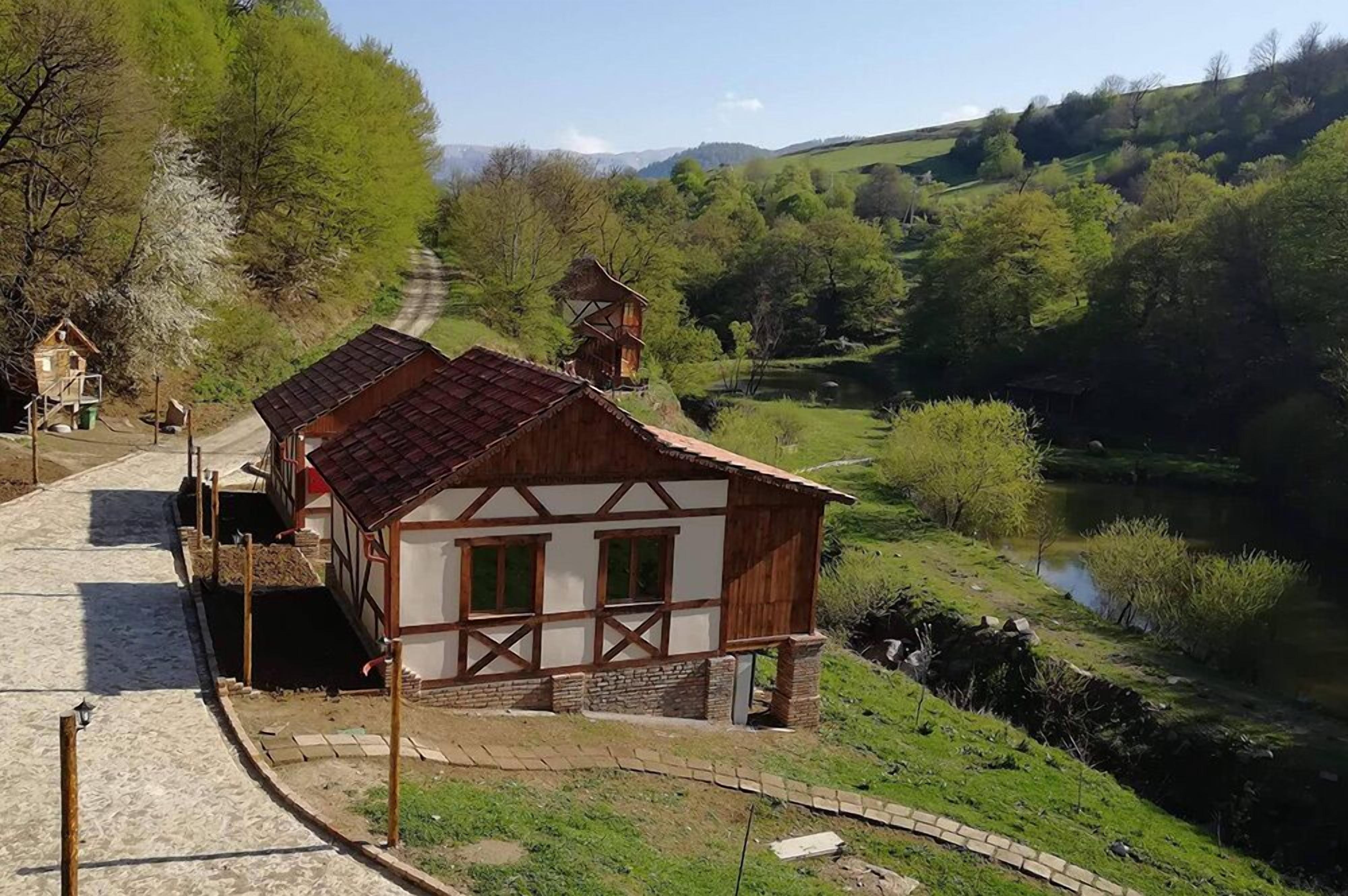 Una casa de madera tradicional con techo inclinado, una pequeña torre y un sendero que la lleva a ella.