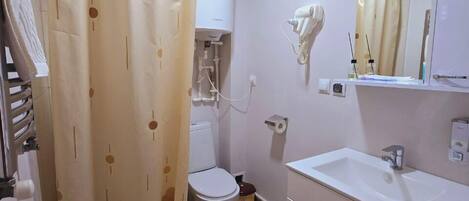 A bathroom with a toilet, a sink, a mirror, and a shower curtain.