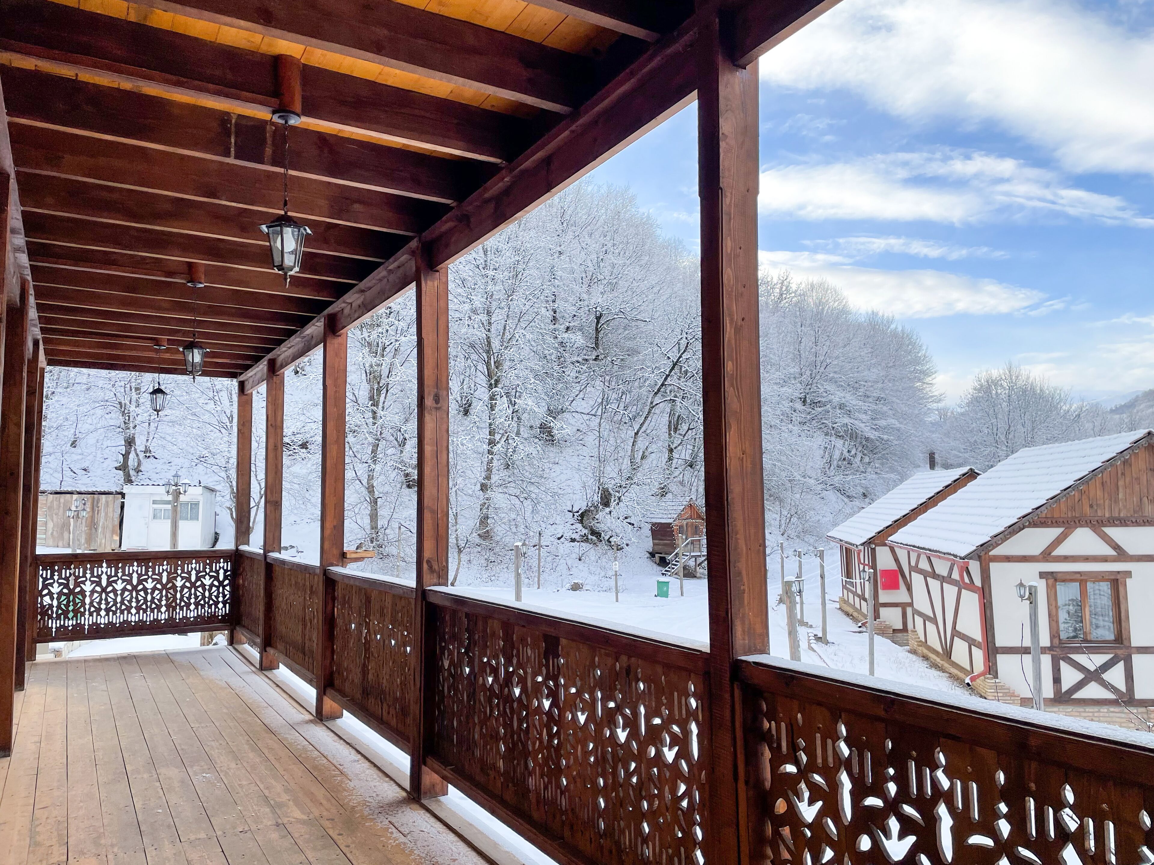 Varanda de madeira com vista para árvores e edifícios cobertos de neve.