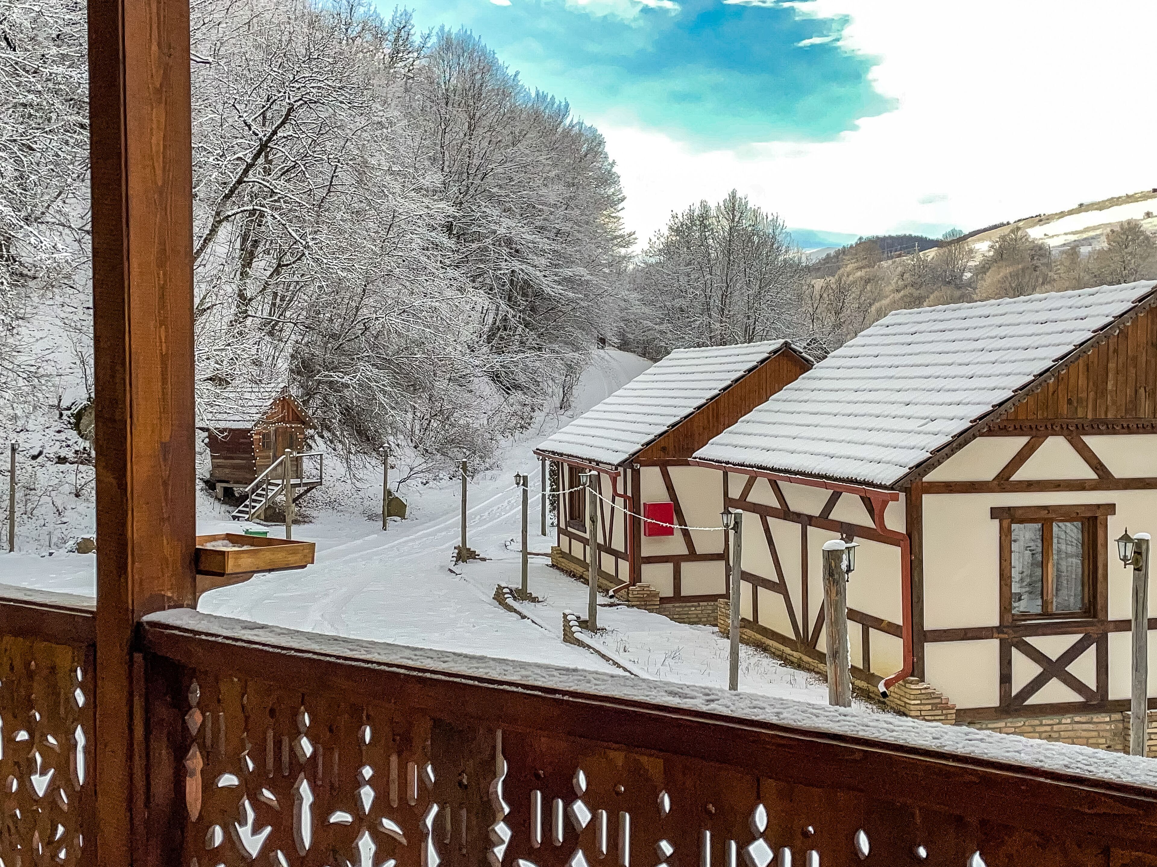 A wooden cabin with a snow-covered roof and a wooden deck.