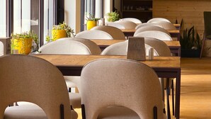 Un espace repas moderne avec des tables et des chaises en bois, des plantes en pot et un comptoir en bois.