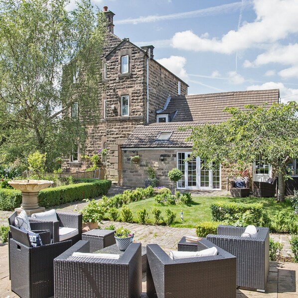 A stone building with a garden and outdoor seating area.