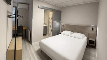 Een moderne hotelkamer met een bed, nachtkastje, lamp en uitzicht op de gang.