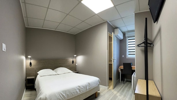 Un dormitorio con cama, mesitas de noche, un escritorio y una televisión.