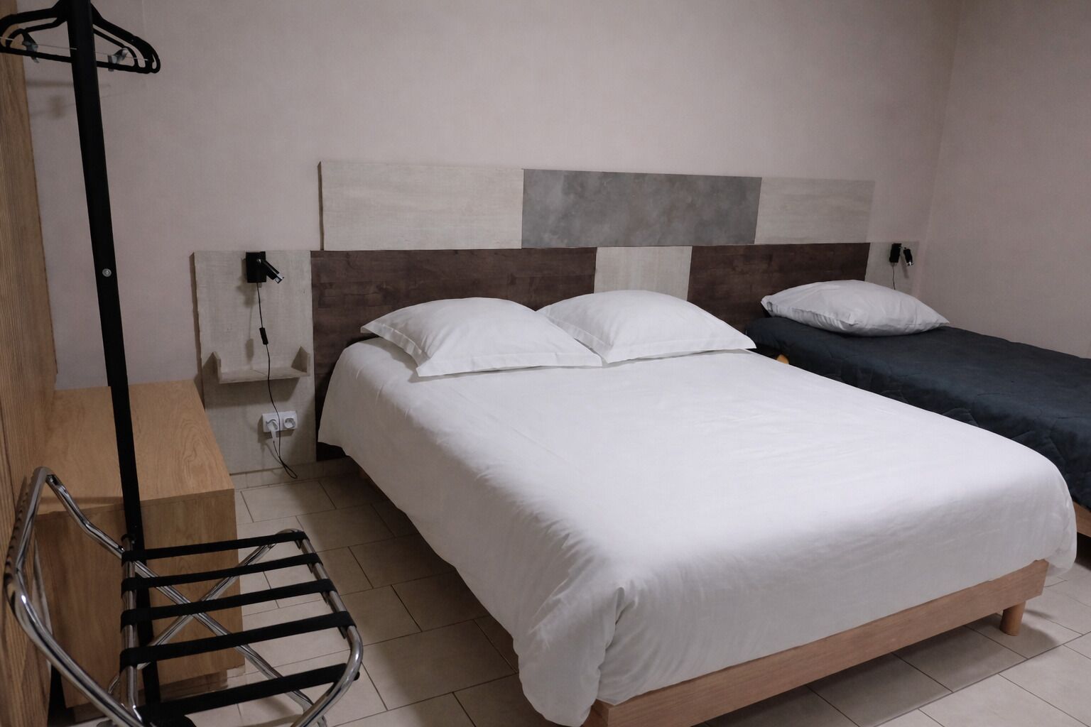 Ein Hotelzimmer mit einem Bett, einem Einzelbett, einem Stuhl und einem Kleiderhaken.