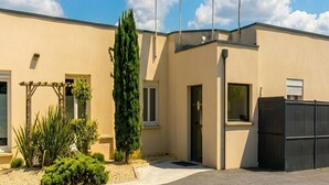 Un hotel llamado 'Hôtel Le Petit Logis', con un letrero, fachada y un pequeño jardín.