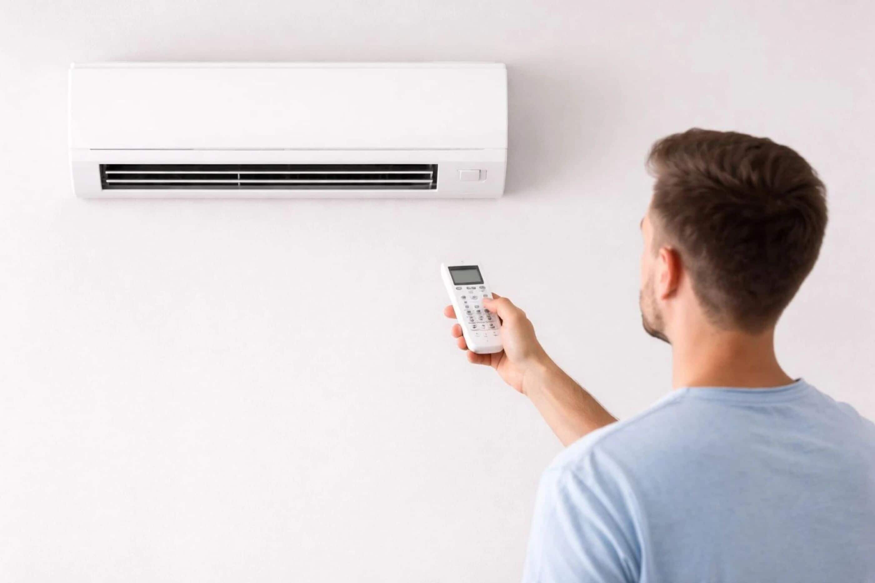 Iemand staat voor een aan de muur bevestigde airconditioning.